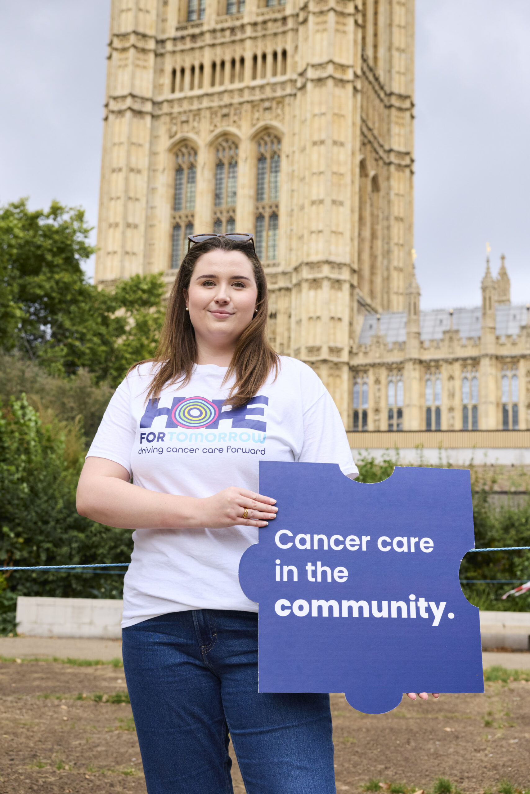 One of our staff members holding our Cancer Care in the Community jigsaw piece in front of Parliament