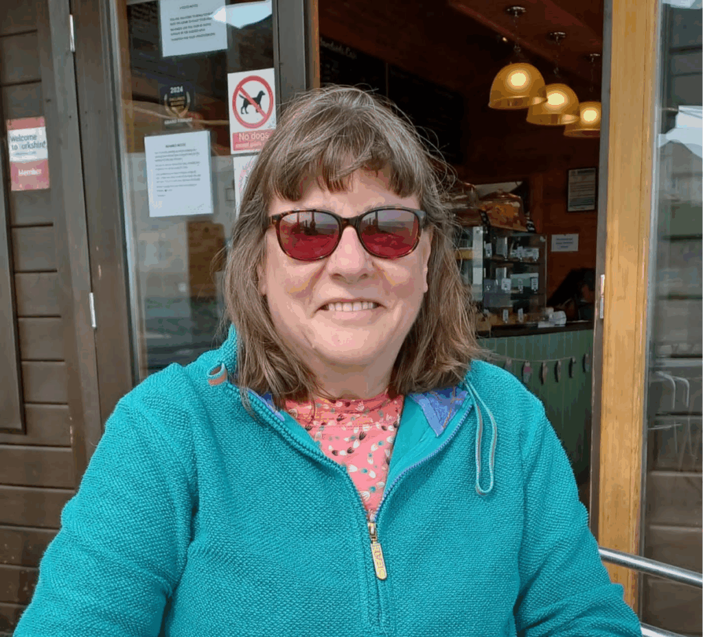 Dora sat outside at a restaurant, looking towards the camer and smiling.