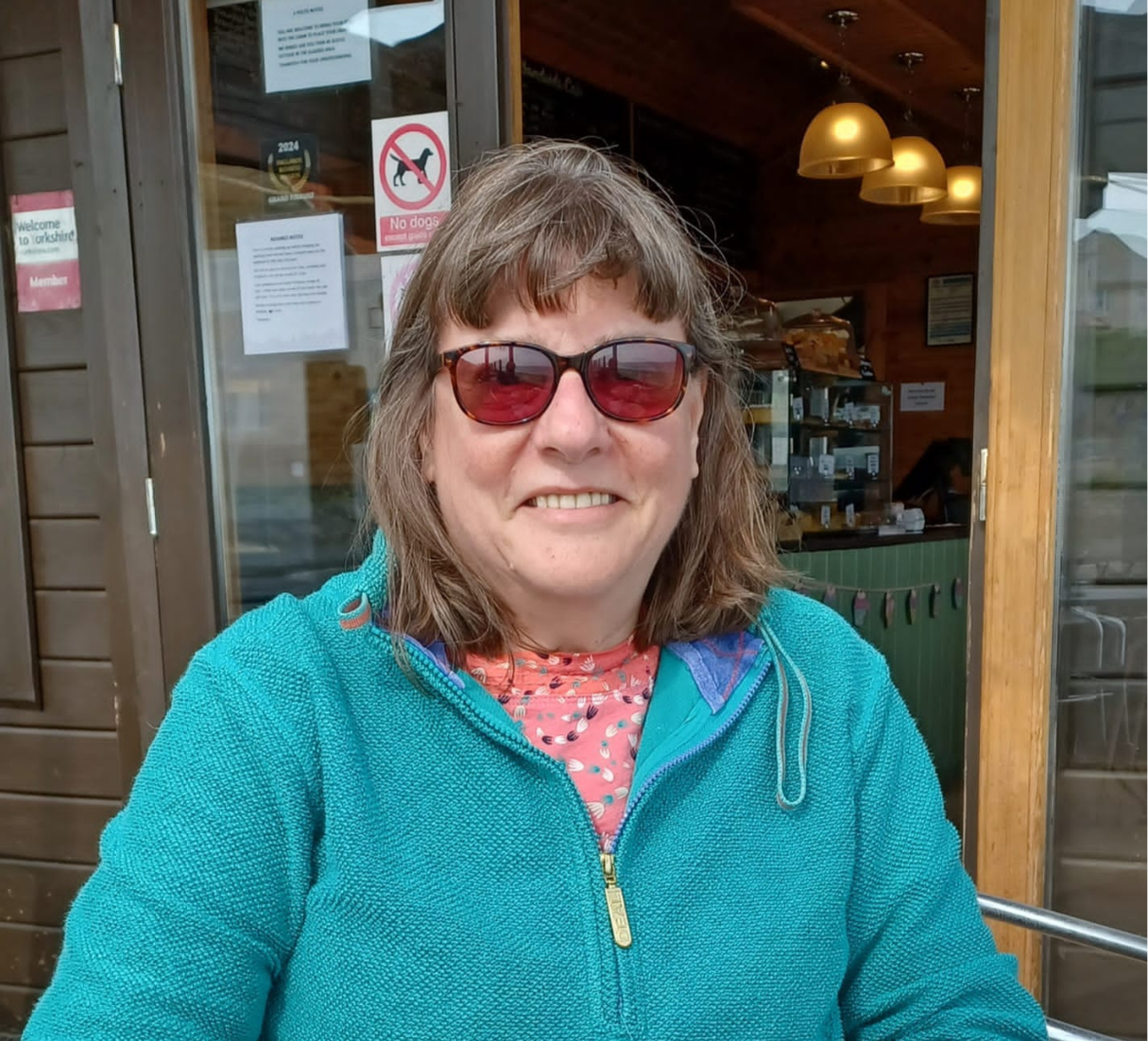 Dora sat outside at a restaurant, looking towards the camer and smiling.