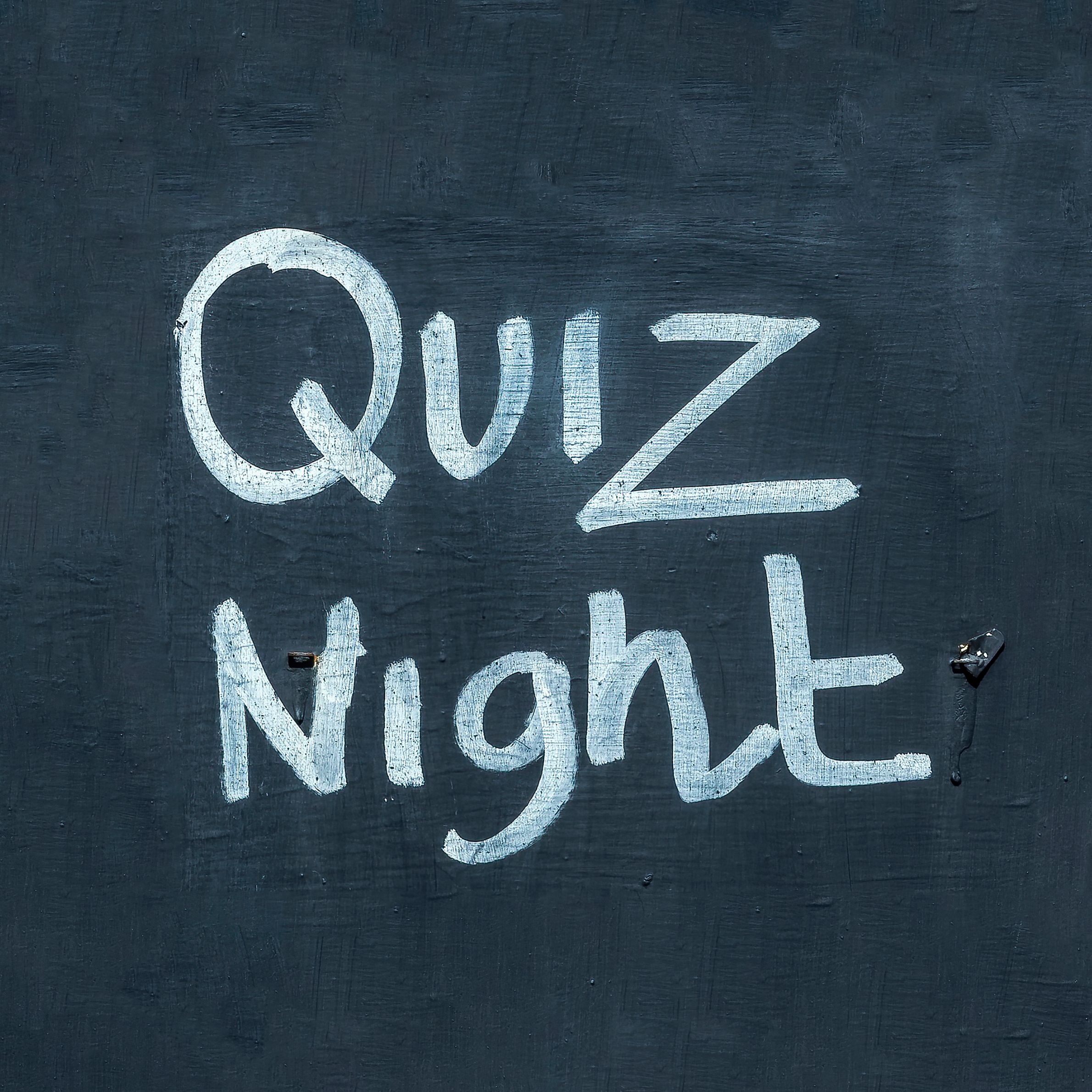 An image showing a chalkboard with handwritten text showing 'quiz night'