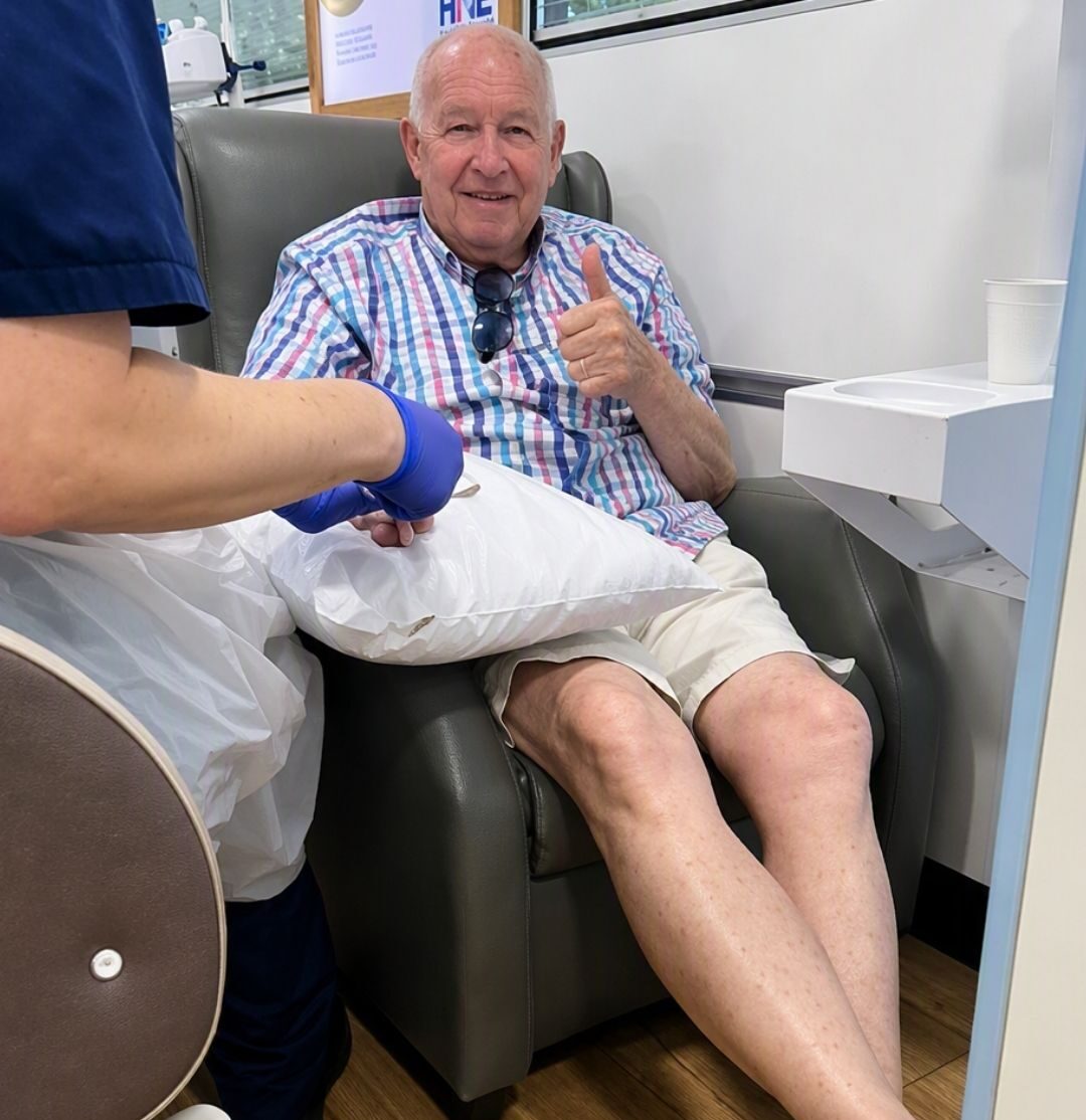 An image showing a gentleman, Paul, having treatment on board a mobile cancer care unit, sitting in a grey chemotherapy chair