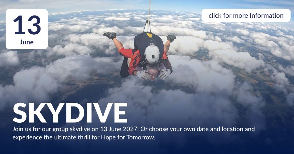 John, a man in his early 40s, jumping from a plane attached to an instructor, wearing his Hope for Tomorrow branded t-shirt